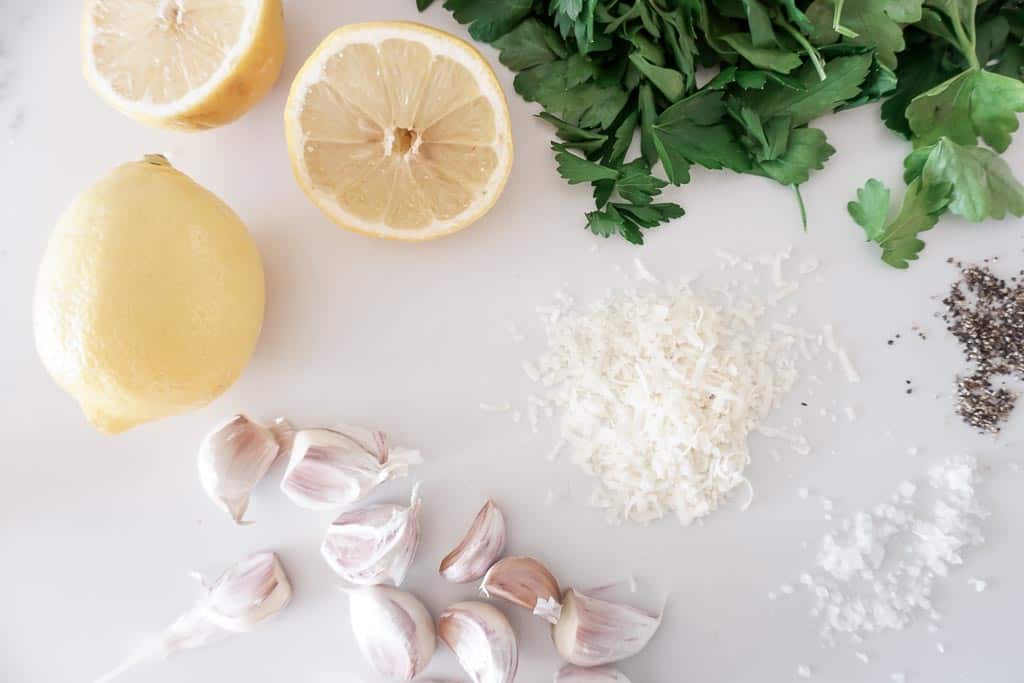 Ingredients to make the pasta from chef the movie. The ingredients include two halved lemons, 15 garlic cloves, parmesan cheese, salt, parsley.