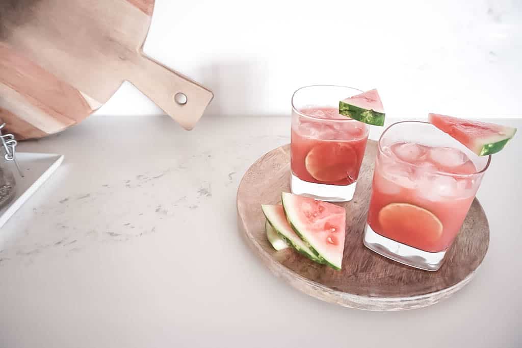 two watermelon margaritas on a wooden serving tray