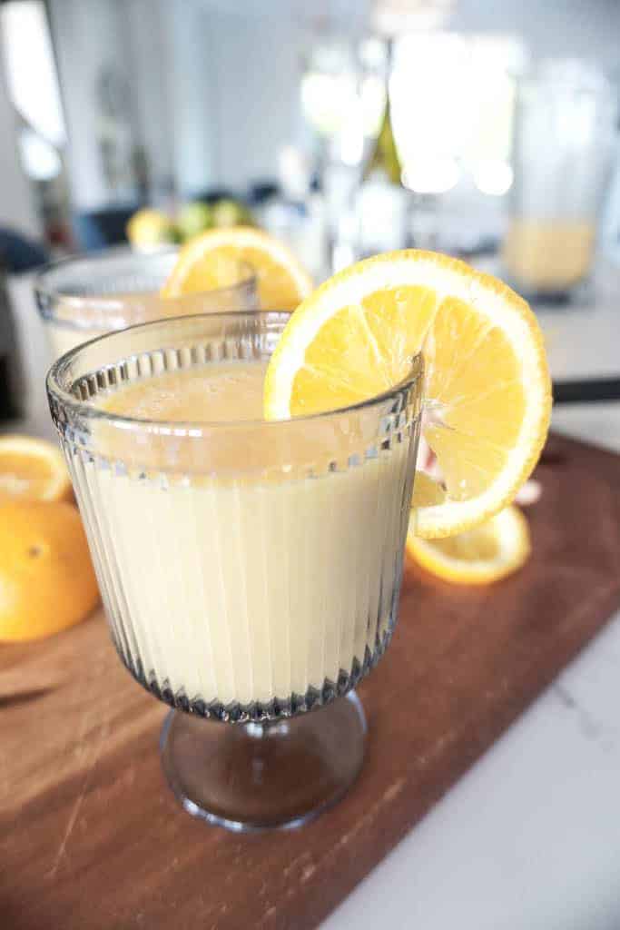 Signed Samantha shared a recipe for wine smoothies. There are two yellow-y orange wine smoothies pictured in blue glasses with a short stem and orange slices on the side.
