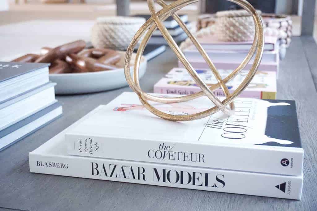 Coffee Table Style using two white coffee table books ( the coveteur and bazar models) along with a gold round shape over top.