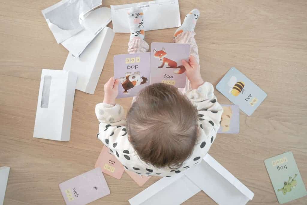 Signed Samantha's Easy and Free Toddler Activities includes putting flash cards into envelopes like what is picture here. Her daughter has a ton of envelopes and flash cards all around her while she stares at her two flash cards