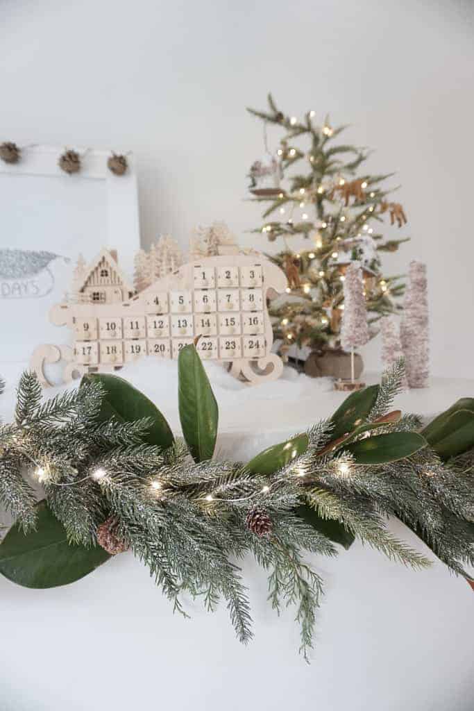 Signed Samantha's holiday mantle decor ideas include fluffing up your garland - as pictured and picking a theme - hers is woodland themed and you can see a wooden sleigh and mini tree above on the mantle.