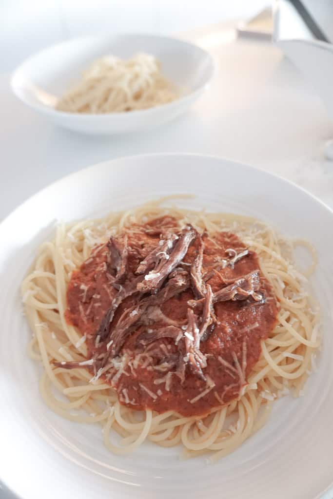 Short Rib Pasta Sauce pictured on a plate over spaghetti noodles