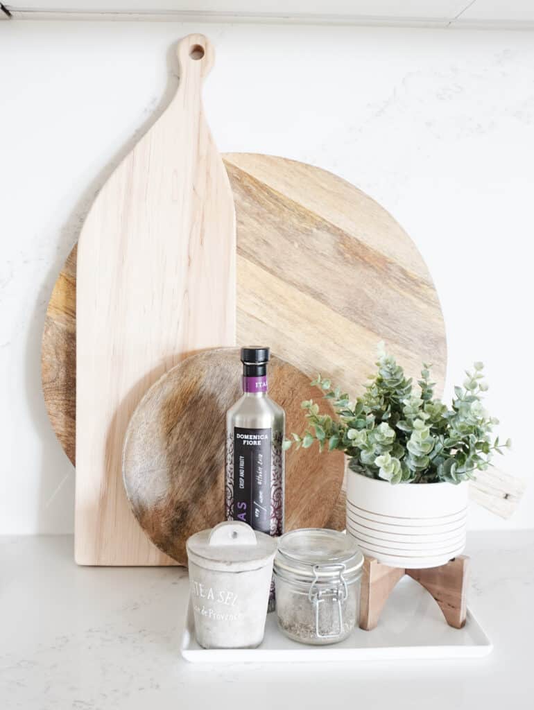 Signed Samantha's home decor refresh tips include updating your greenery in spaces to bring life in - like this eucyalptus plant in front of wood cutting boards, evoo, and salt and pepper in the kitchen.