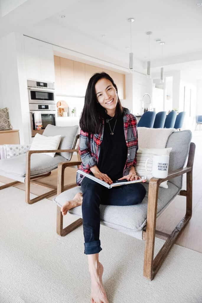 Signed Samantha's January Champagne Chats (Q&A) and self-care as she is sitting on a chair in the living room(with the kitchen in the background) going through her cook books