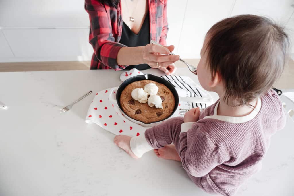 Signed Samantha feeding her daughter Sloane a piece of her gluten-free chocolate chip skillet cookie straight from the pan