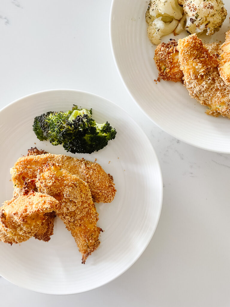 Sneaky mommy chicken strips are on a plate with some broccoli which is less sneaky than the chicken strips that have zuchinni on them.