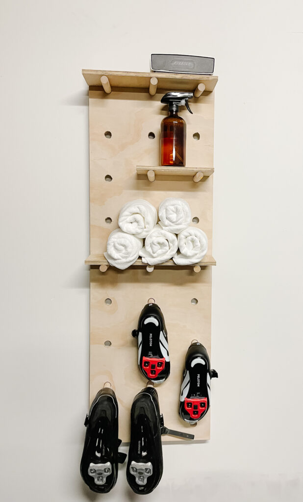 Samantha's DIY pegboard with towels, spray bottles, and biking shoes on it