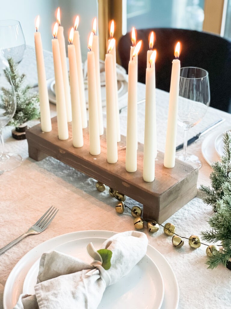 A beautiful tablescape with a DIY tapered candle holder in the middle, mini table trees, fable dinnerware.