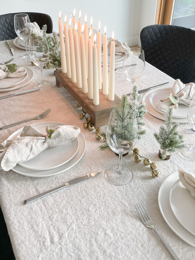 A beautiful tablescape with a DIY tapered candle holder in the middle, mini table trees, fable dinnerware.