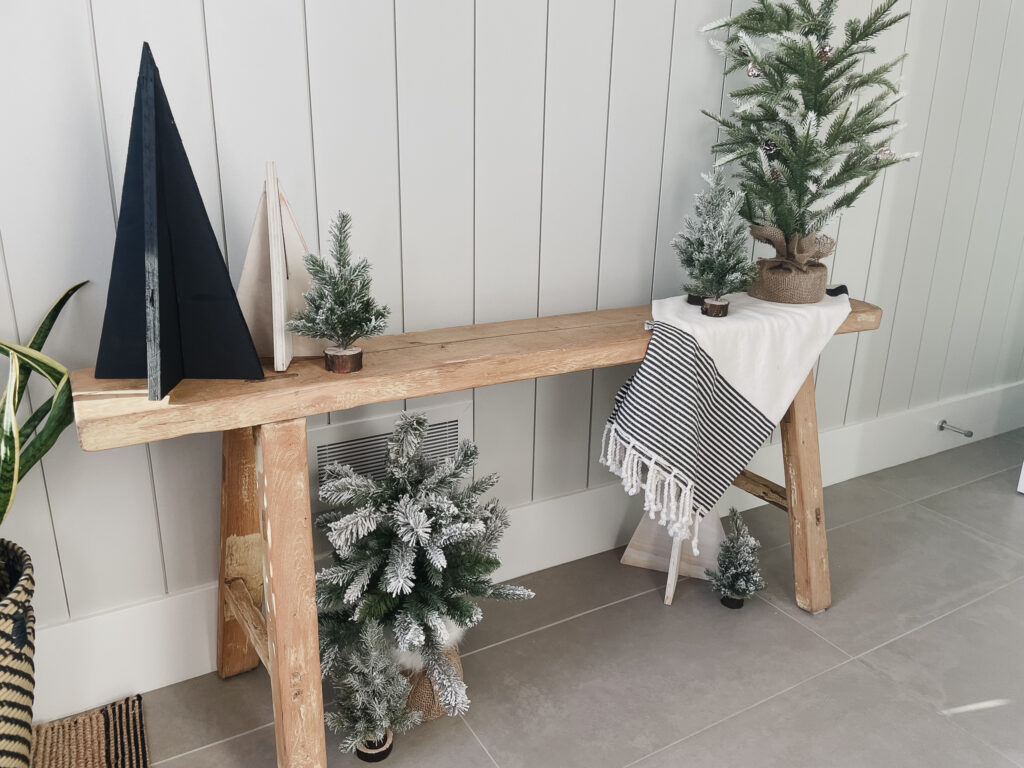 DIY Wood Christmas trees ontop of a bench with faux small christmas trees around.