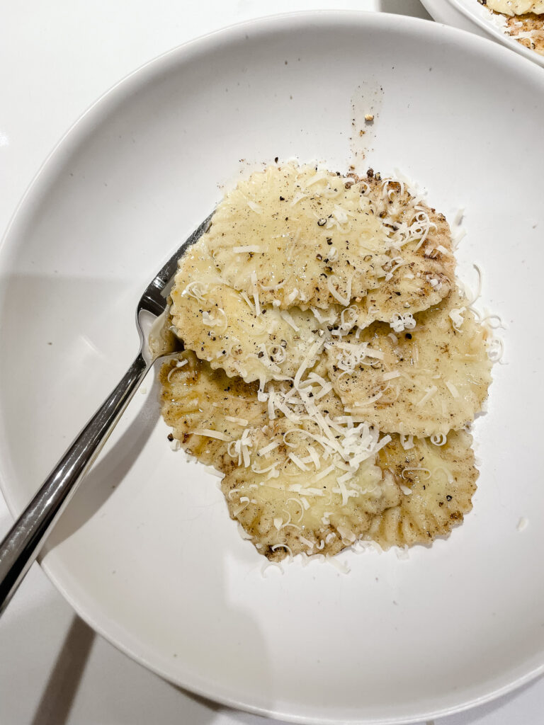 gluten-free ravioli pictured with brown butter sauce and pamesan over top
