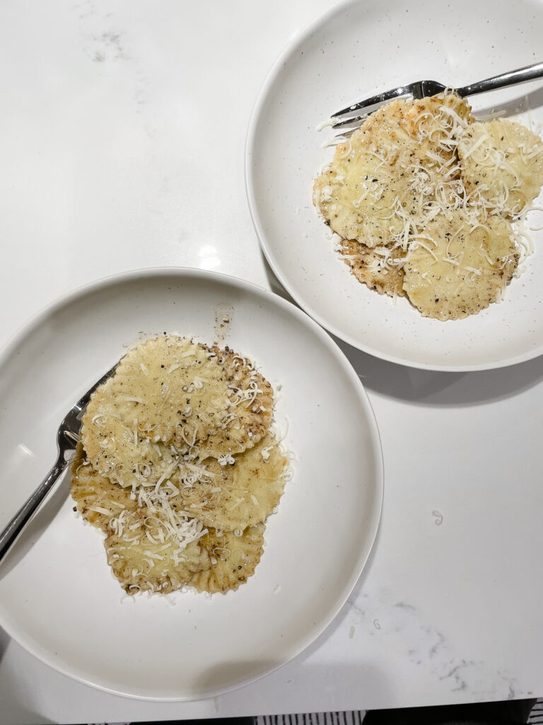 two plates of gluten-free ravioli pictured with brown butter sauce and pamesan over top