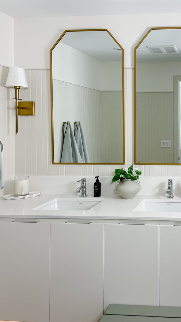 beadboard on this beautifully upgraded bathroom with gold mirrors and wall sconces.