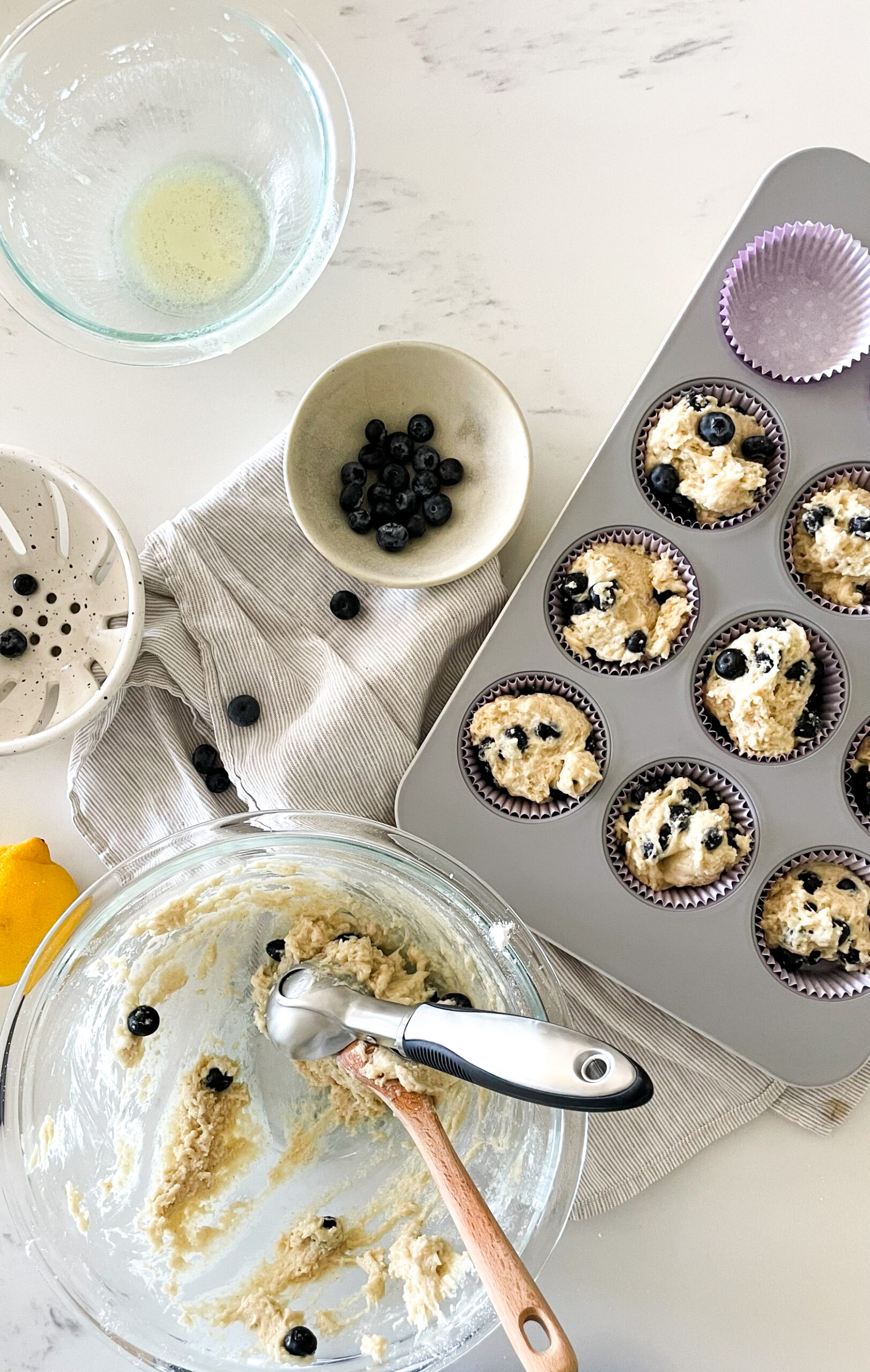 preparing gluten-free blueberry lemon muffins - uncooked batter in the muffin tin and an empty mixing bowl off to the side