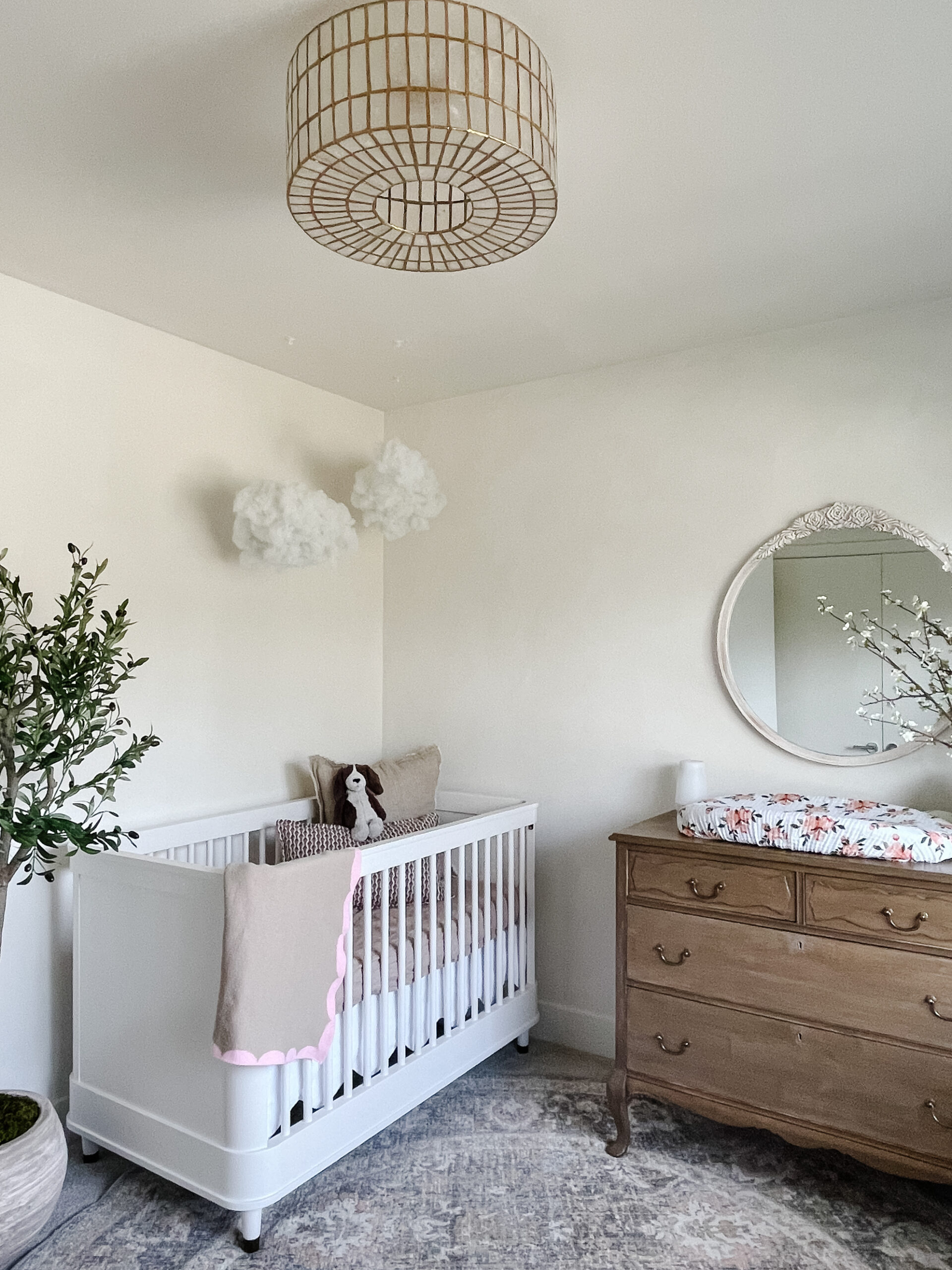 Calming nursery reveal with lime washed walls, an antiqued upcyled dresser, faux clouds, olive tree, and distressed mirror