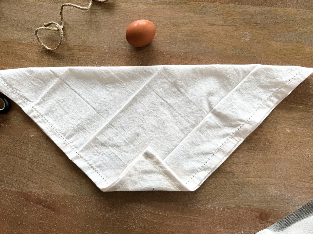 how to do a bunny ear easter napkin fold with a napkin in a triangle about to be rolled up