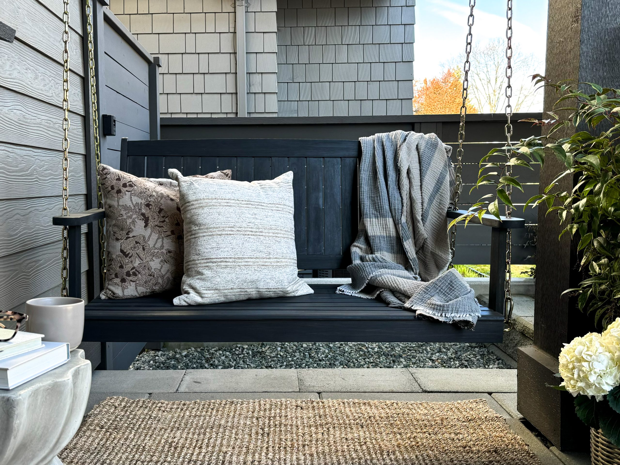 creating the perfect outdoor oasis with products from Wayfair Canada including a porch swing, cozy pillows, blankets, and affordable plant pots.