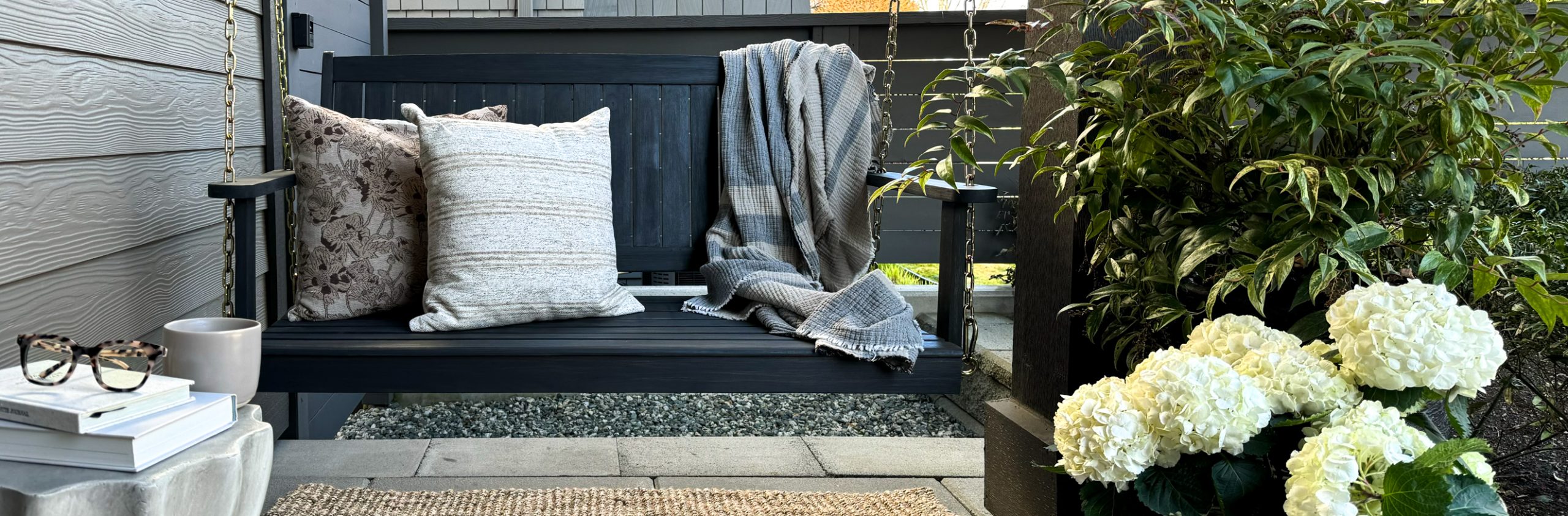 creating the perfect outdoor oasis with products from Wayfair Canada including a porch swing, cozy pillows, blankets, and affordable plant pots.